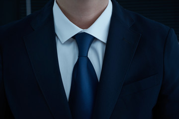 Part of man body side folded his arms in black suit on black background, business concept .