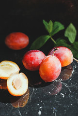 fresh plum on a black background with green leaves