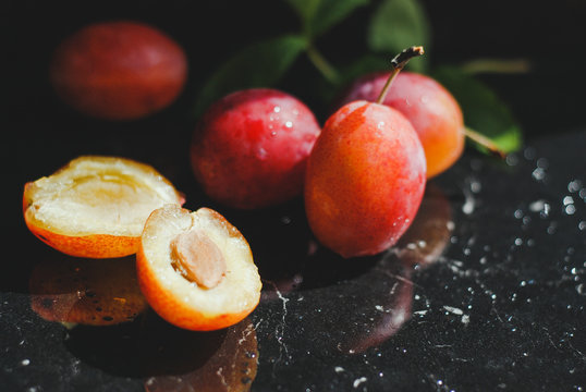 fresh plum on a black background with green leaves