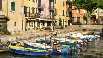 Fototapeta na wymiar Gardasee Brenzone der kleine Hafen in der Abendsonne. Bunte Häuser, bunte Boote, Italienisches Flair. 