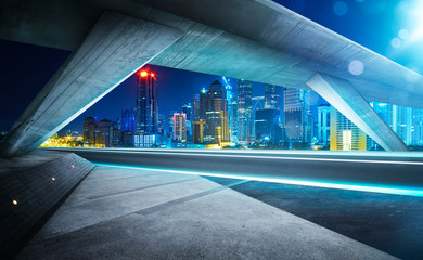 Obraz na płótnie Canvas Empty asphalt road under the bridge during the night with beautiful city skyline background .
