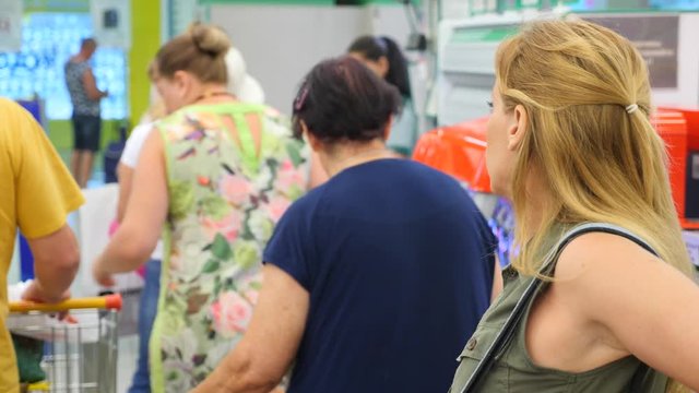 The queue of people standing at the checkout in the supermarket. 4k, slow motion