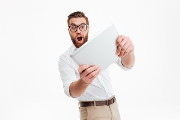 Handsome young bearded man play games by tablet computer.