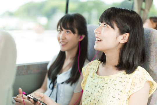 Two Young Women Sharing Headphone on Bus