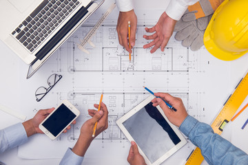 Hands of professional architects discussing and working with blueprints
