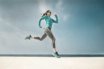 Fototapeta premium Woman running along the sealine coast under sunlight at sunny su
