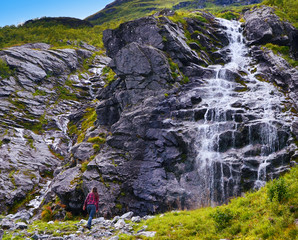 Hjorundfjord, Norway - October 2nd, 2017: Girl hiking to a Waterfall in Sunmore Alps, near Hjorundfjord, Norway