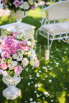 vases with tender pink flowers outdoor on the grass. Wedding decorations and floristic