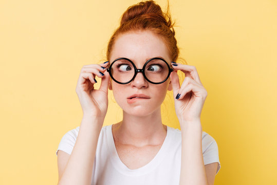 Close-up picture of funny ginger woman in eyeglasess showing grimace