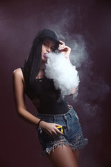 Young sexy woman is vaping. A cloud of vapor. Studio shooting.