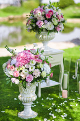 vases with tender pink flowers outdoor on the grass. Wedding decorations and floristic