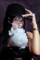 Young sexy woman is vaping. A cloud of vapor. Studio shooting.