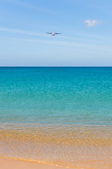 Airplane landing above beautiful beach and sea background