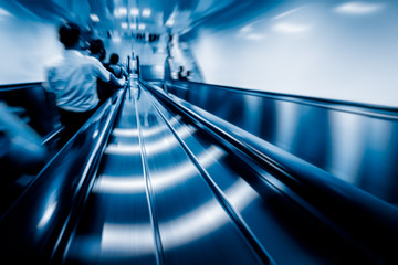 business people rushing on the escalator in motion blur on the subway station.