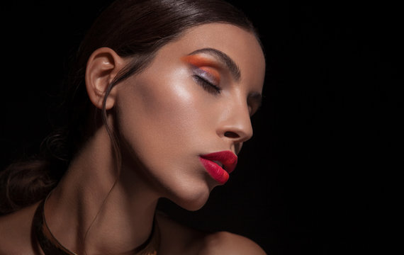 Beautiful young woman with red lips and vibrant eyeshadow on black background