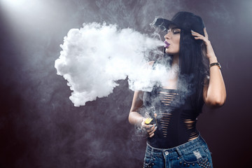 Young sexy woman is vaping. A cloud of vapor. Studio shooting.