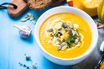 Pumpkin and carrot cream soup on blue.