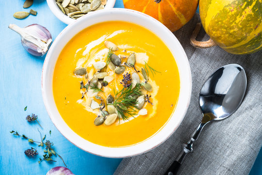 Pumpkin and carrot cream soup on blue.