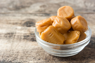 Toffee caramel candies in a crystal bowl on wooden table
