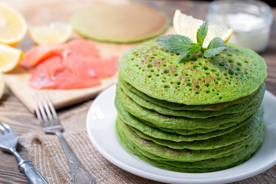 A stack of pancakes of spinach. On the table along with the fish, spinach and lemon wedges.