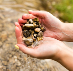 Small stones in the hand on the pond