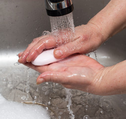 Fototapeta premium Woman washes her hands with soap under a tap of water