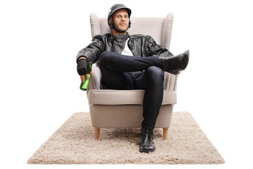 Biker with a bottle of beer sitting in an armchair