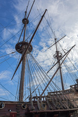 Obraz premium The masts of old wooden galleone on blue sky background in port of Genoa, Italy