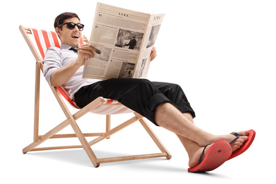 Businessman sitting in a deck chair and reading a newspaper