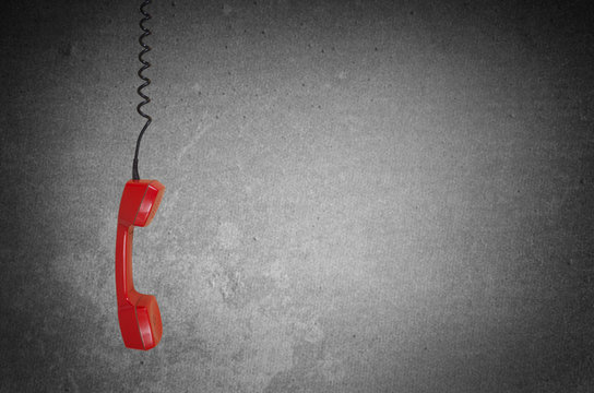 Red telephone receiver over gray background with copy space