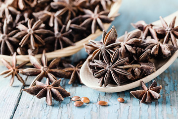 Whole star anise in a basket and spoon on wooden background