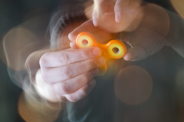 Young man spinning the spinner device in his fingers. Blurred fast motion. Popular toy device in...
