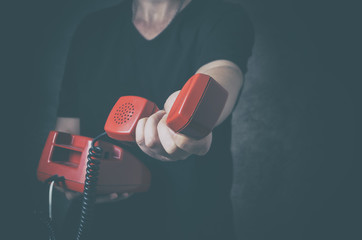 SOS phone or helpline for people in personal crisis - unrecognizable man with old red phone in hand