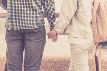 A guy and a girl are holding hands together and looking at the sea