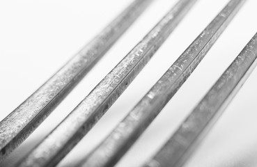 A close shot of the tines of a single silver fork on a white background showing regular wear and...