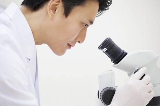 Side view of male scientist using microscope