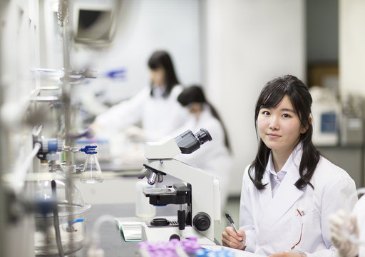 Female student smiling in front of microscope