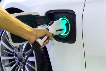 Closes up Human hand is holding Electric Car Charging connect to Electric car with green light display full battery.