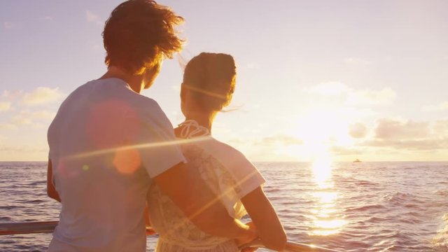 Cruise ship vacation couple enjoying sunset view sailing on small cruise boat at sea. Romantic couple on honeymoon travel at sea looking at sunset. RED EPIC SLOW MOTION.