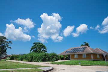 Solar panels on the roof of suburban house at street corner under cloud blue sky. Photovoltaic...