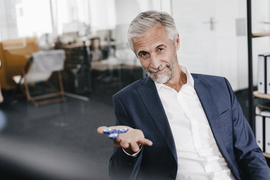Portrait of mature businessman in office with fidget spinner