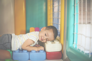 Little boy in playground. Boy lying on cubes.