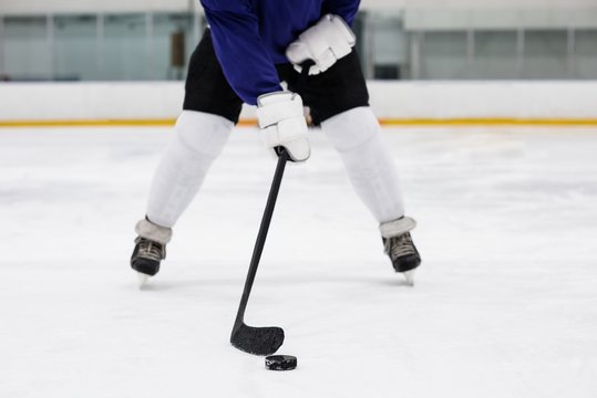 Low section of player playing ice hockey at rink