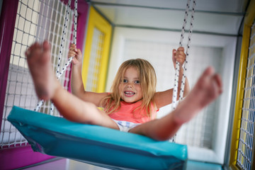 Little girl in playground. Girl is rocking on the swing.