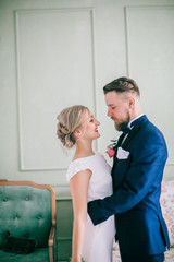 Chic wedding couple groom and bride posing in a white Studio. Happy couple laughing. White dress. ...