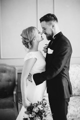 Chic wedding couple groom and bride posing in a white Studio. Happy couple laughing. White dress. ...