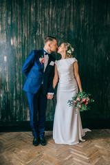 cute wedding couple in the interior of a classic studio decorated. they kiss and hug each other. Newkyweds looking. Bride and groom photoshoot