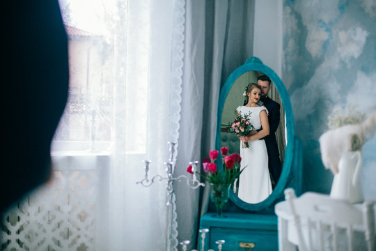 Vintage mirror with the bride and groom in the reflection in interior studio on the wedding day