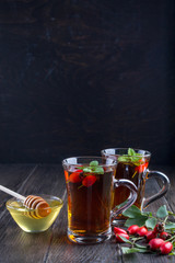 Healthy autumn drink with hip roses ,branch with berries on dark  background. 