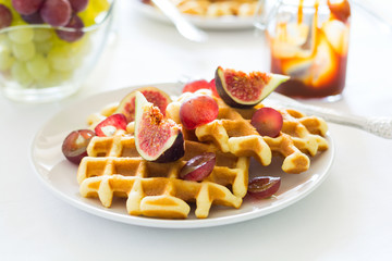 Healthy breakfast: Belgian waffles with figs, grapes and caramel on white table cloth. Selective focus